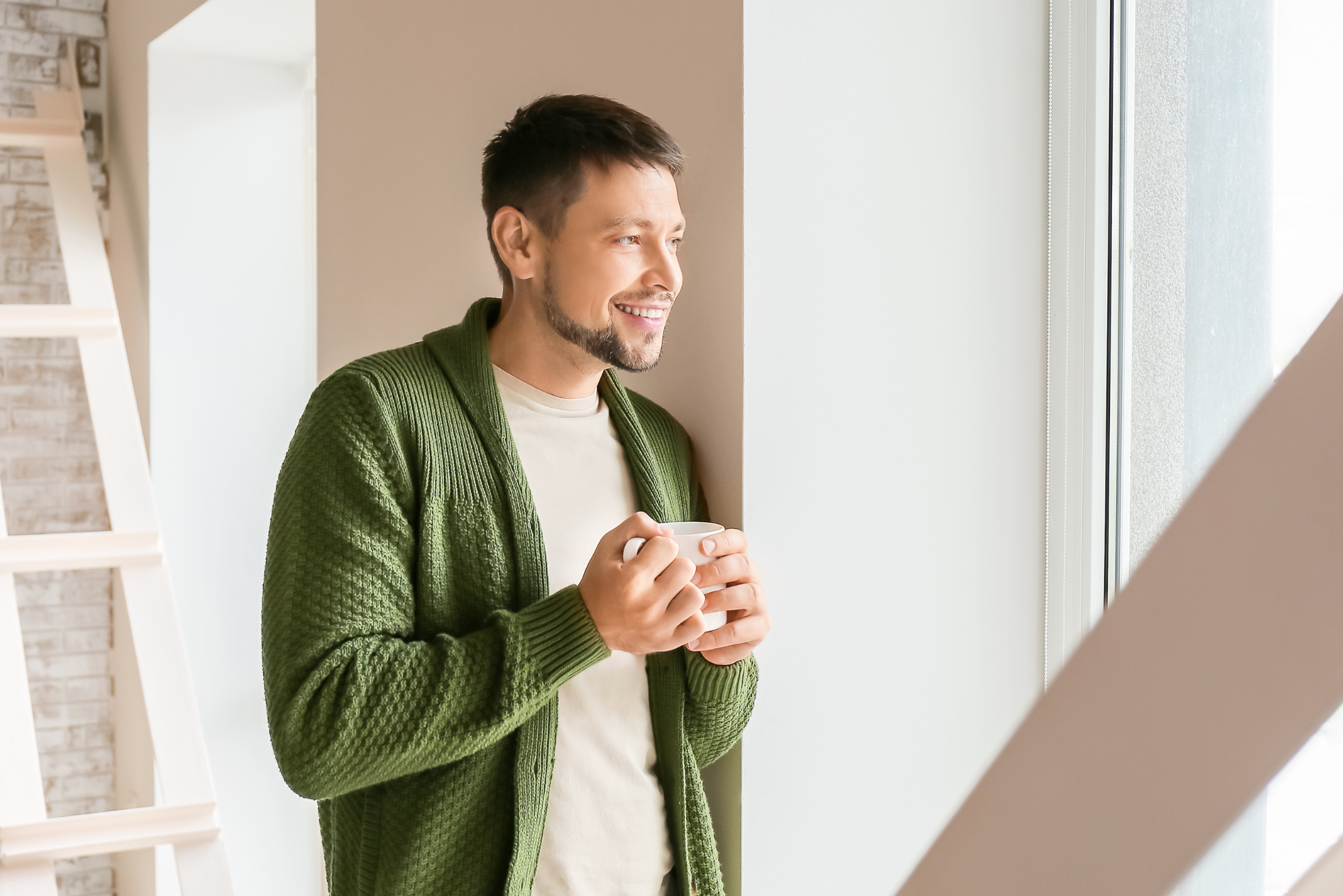 Man enjoying a cup of tea by a window.